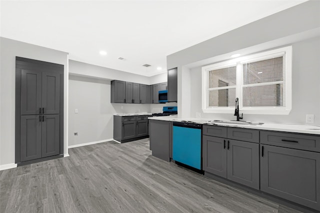 5538 Berry Creek Dr, Houston, TX 77017 - kitchen with light wood-style floors, dishwashing machine, stainless steel microwave, gas range oven, and gray cabinetry
