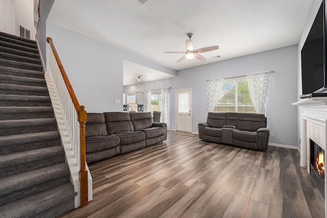 13134 Durbridge Trail Dr, Houston, TX 77065 - living area with a warm lit fireplace, ceiling fan, wood finished floors, and stairs