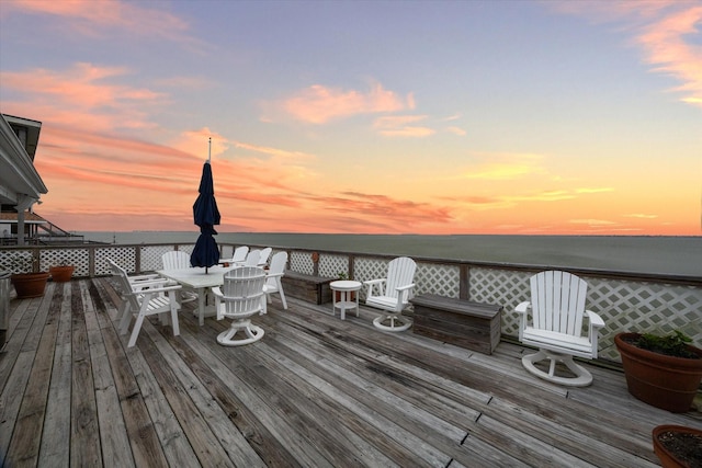 deck with outdoor dining space and a water view
