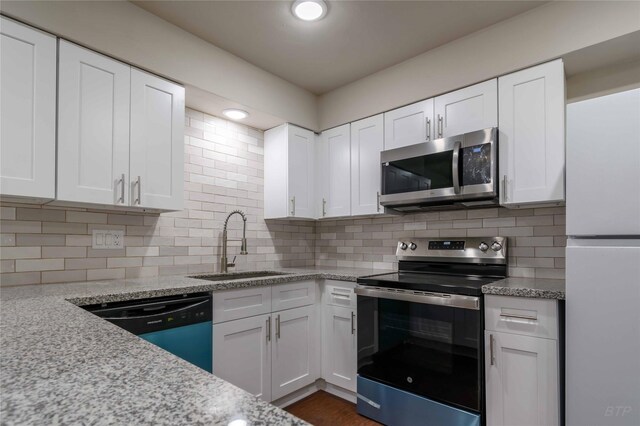 12046 Beechnut St, Houston, TX 77072 - kitchen with stainless steel appliances, light stone countertops, white cabinetry, and a sink