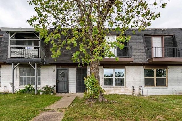 12046 Beechnut St, Houston, TX 77072 - view of front facade with a front yard, brick siding, a balcony, and mansard roof
