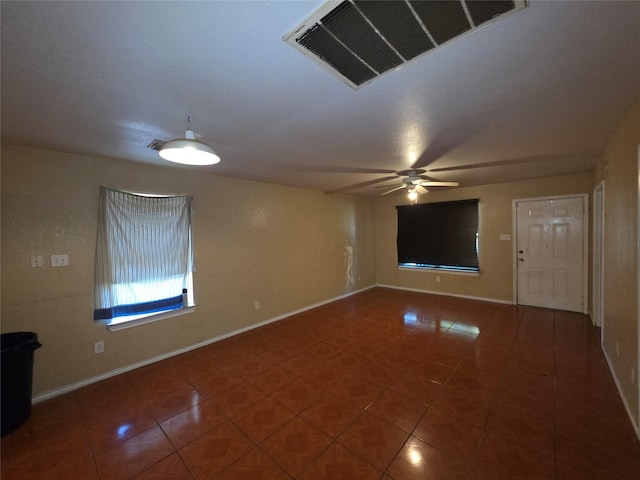 tiled spare room featuring visible vents, baseboards, and a ceiling fan