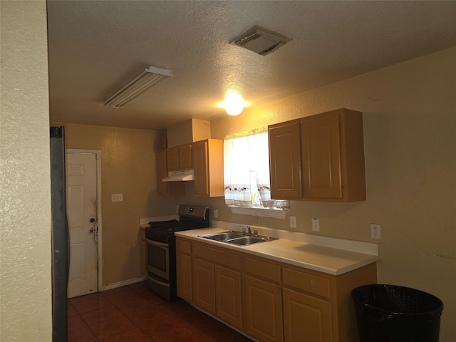 kitchen with visible vents, gas range, under cabinet range hood, light countertops, and a sink