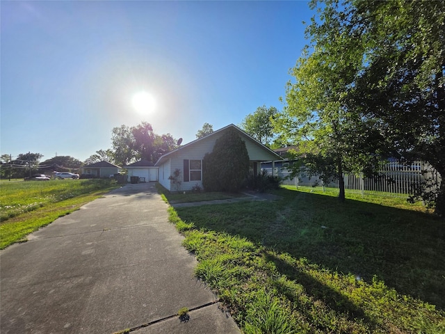bungalow-style home with concrete driveway, a garage, fence, and a front lawn