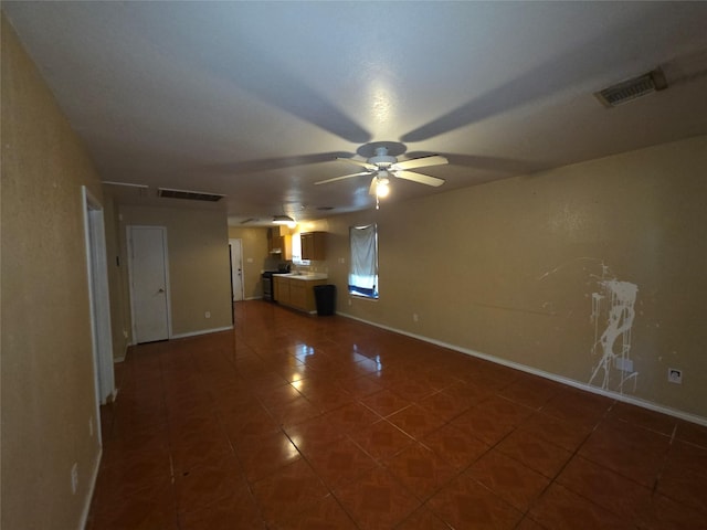 unfurnished living room with baseboards, dark tile patterned floors, and visible vents