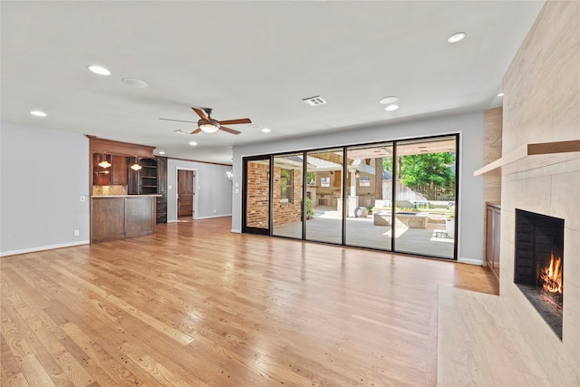 unfurnished living room with light wood-type flooring, a ceiling fan, recessed lighting, and a tile fireplace