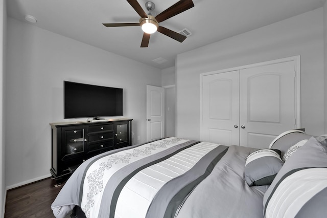 bedroom with dark wood-style floors, visible vents, a closet, baseboards, and ceiling fan