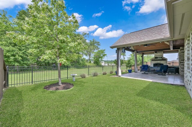 view of yard with an outdoor living space with a fireplace, a patio area, a fenced backyard, and a ceiling fan