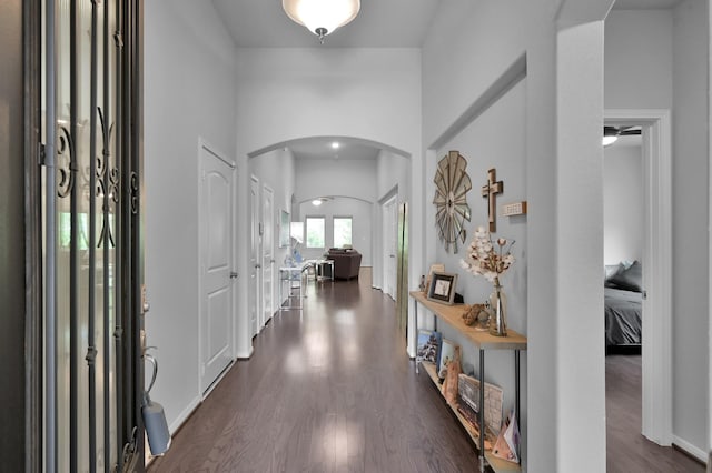 foyer entrance with arched walkways and dark wood-style flooring