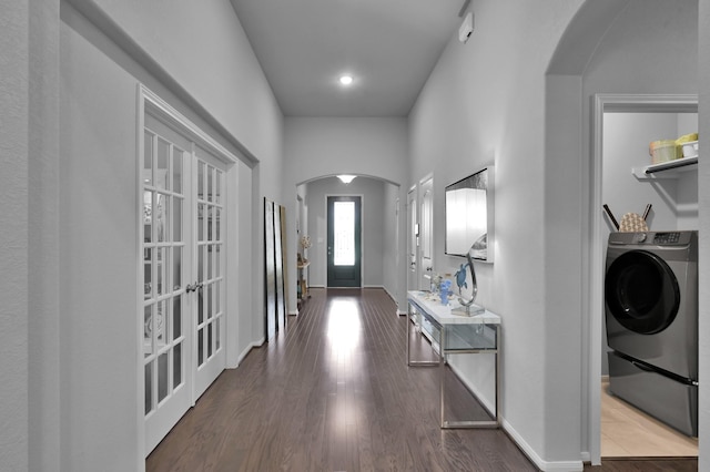 entryway with baseboards, wood finished floors, arched walkways, and washer / dryer
