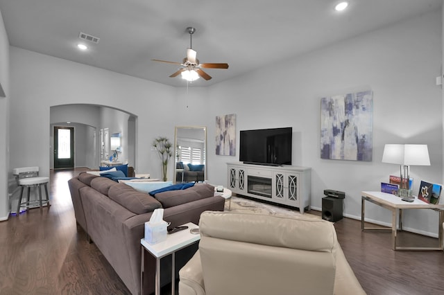 living room featuring arched walkways, visible vents, a ceiling fan, and dark wood-type flooring
