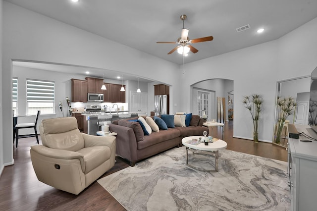 living area featuring arched walkways, dark wood finished floors, visible vents, recessed lighting, and a ceiling fan