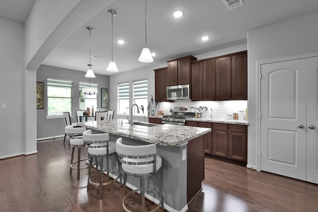 kitchen featuring light stone countertops, dark wood-style floors, a sink, and appliances with stainless steel finishes