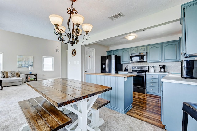 kitchen featuring dark colored carpet, a center island, blue cabinetry, visible vents, and appliances with stainless steel finishes
