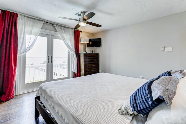 bedroom featuring a ceiling fan, a textured ceiling, wood finished floors, french doors, and access to exterior