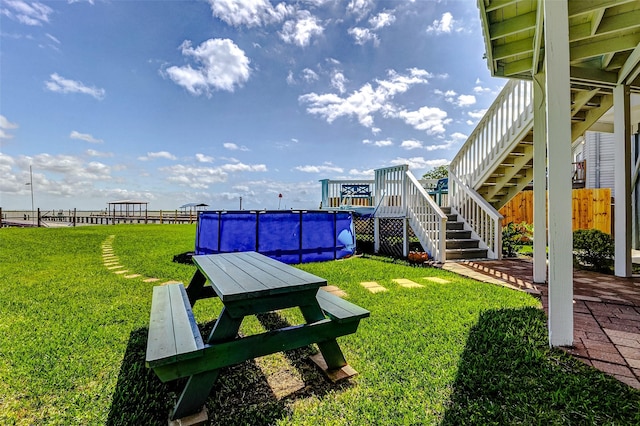 view of yard featuring an outdoor pool, a wooden deck, fence, and stairs