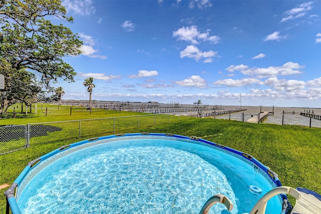 view of swimming pool featuring a yard and fence
