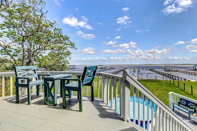 wooden deck featuring a water view, a lawn, and a fenced in pool