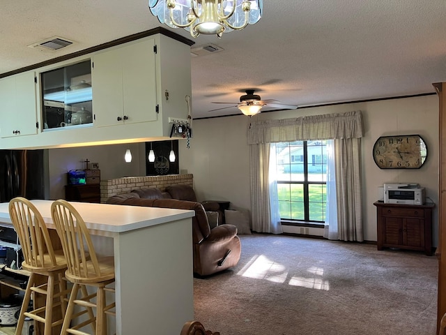 kitchen with visible vents, a textured ceiling, carpet flooring, and ceiling fan with notable chandelier