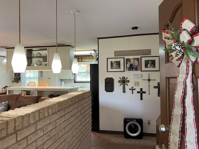 kitchen with a wealth of natural light, dark colored carpet, decorative light fixtures, and a textured ceiling