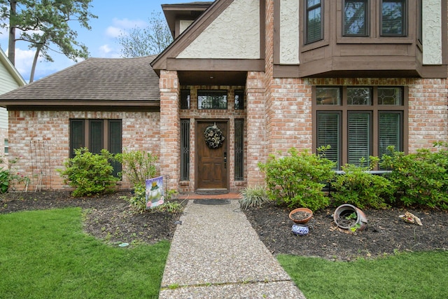 entrance to property featuring brick siding and a shingled roof