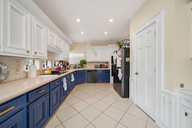 kitchen with tasteful backsplash, light tile patterned floors, white cabinets, black appliances, and blue cabinetry