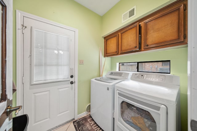 washroom with light tile patterned flooring, visible vents, washing machine and clothes dryer, and cabinet space