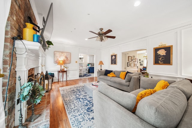 living area with a decorative wall, light wood-type flooring, a ceiling fan, and recessed lighting