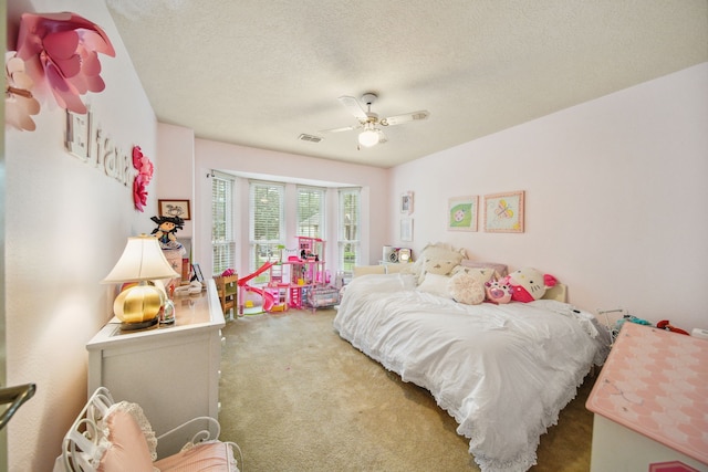 bedroom featuring carpet, visible vents, a textured ceiling, and a ceiling fan