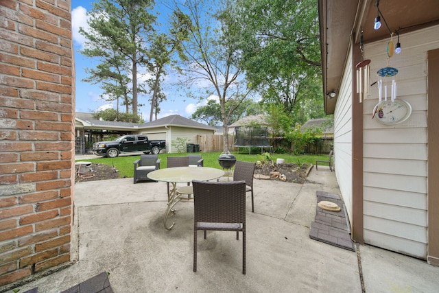 view of patio / terrace with a trampoline, fence, and outdoor dining space