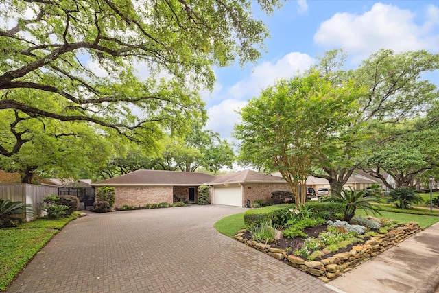 ranch-style home with a garage, fence, and decorative driveway