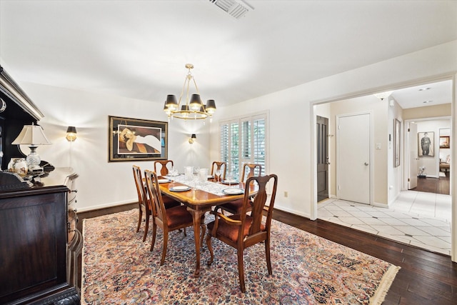 dining room with visible vents, baseboards, a chandelier, and hardwood / wood-style flooring