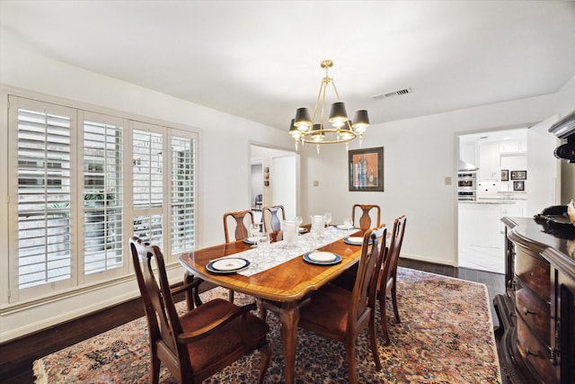 dining room with dark wood-type flooring, baseboards, a notable chandelier, and visible vents