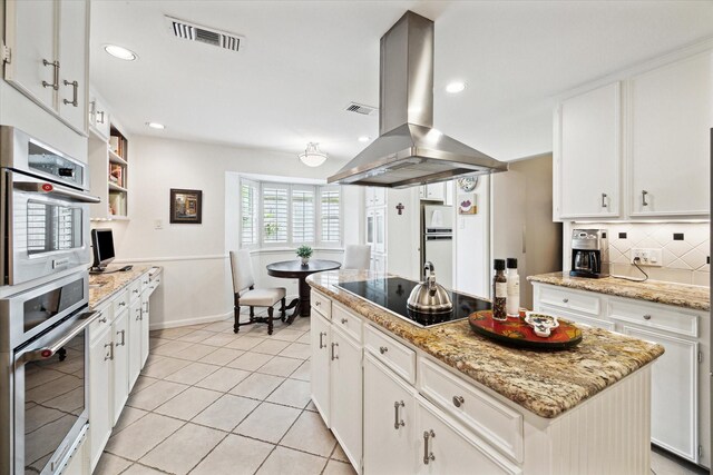 kitchen featuring island exhaust hood, white cabinetry, a kitchen island, visible vents, and double oven