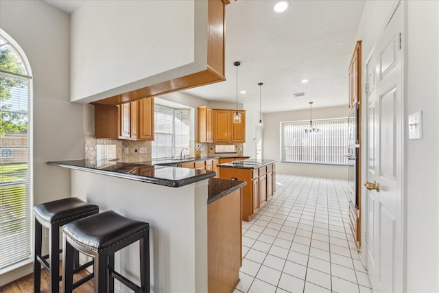 kitchen featuring plenty of natural light, a peninsula, a center island, and dark countertops