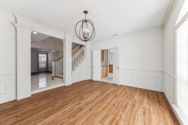 interior space with a decorative wall, ornamental molding, light wood-type flooring, decorative columns, and stairway
