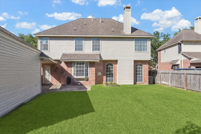 back of property featuring a lawn, a patio area, fence, brick siding, and a chimney