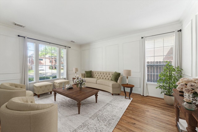 living room with a decorative wall, visible vents, and ornamental molding