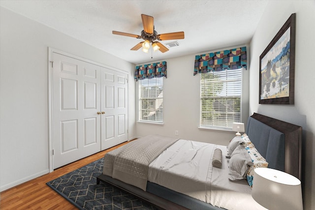 bedroom featuring ceiling fan, a closet, visible vents, wood finished floors, and baseboards