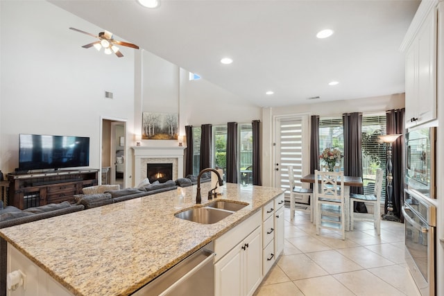 122 Verismo Ct, Montgomery, TX 77316 - kitchen featuring light tile patterned floors, a warm lit fireplace, light stone counters, a sink, and stainless steel appliances