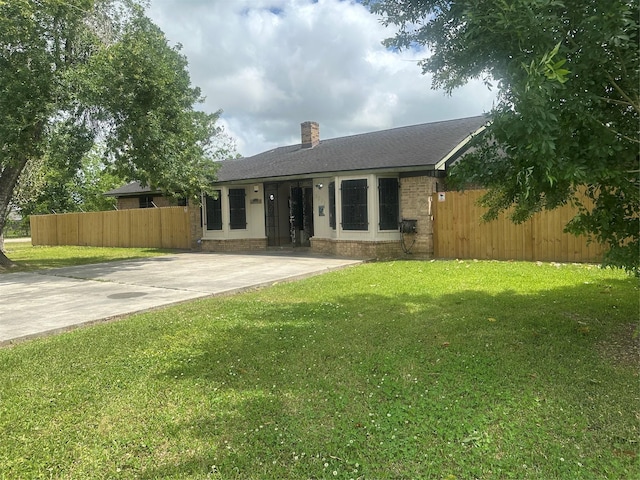 view of front of home with roof with shingles, a chimney, fence, brick siding, and a front yard