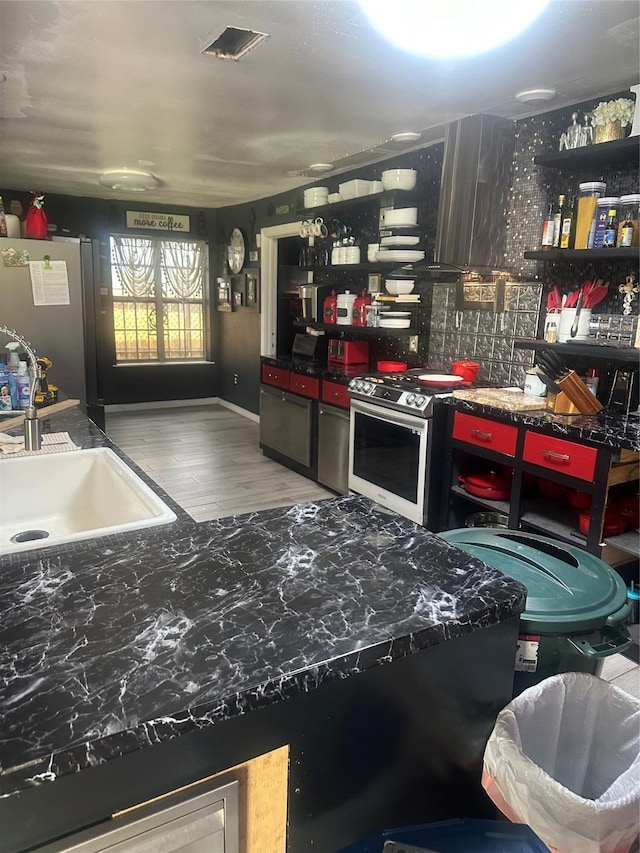 kitchen featuring dark countertops, appliances with stainless steel finishes, wood finished floors, and a sink