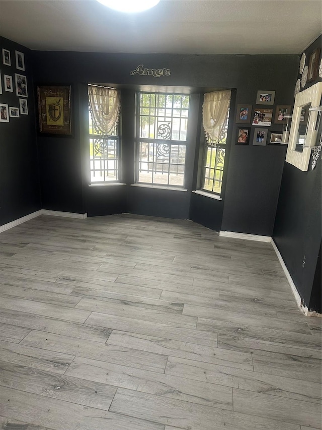 spare room featuring baseboards and wood finished floors