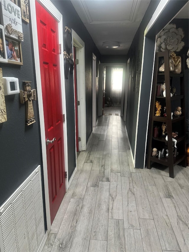 hall with attic access, visible vents, and light wood-style flooring