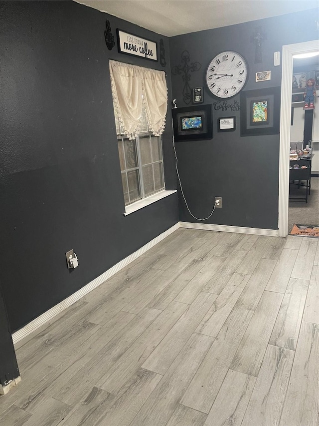 spare room with baseboards and wood finished floors