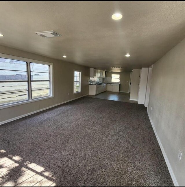 unfurnished living room featuring dark carpet, baseboards, and recessed lighting