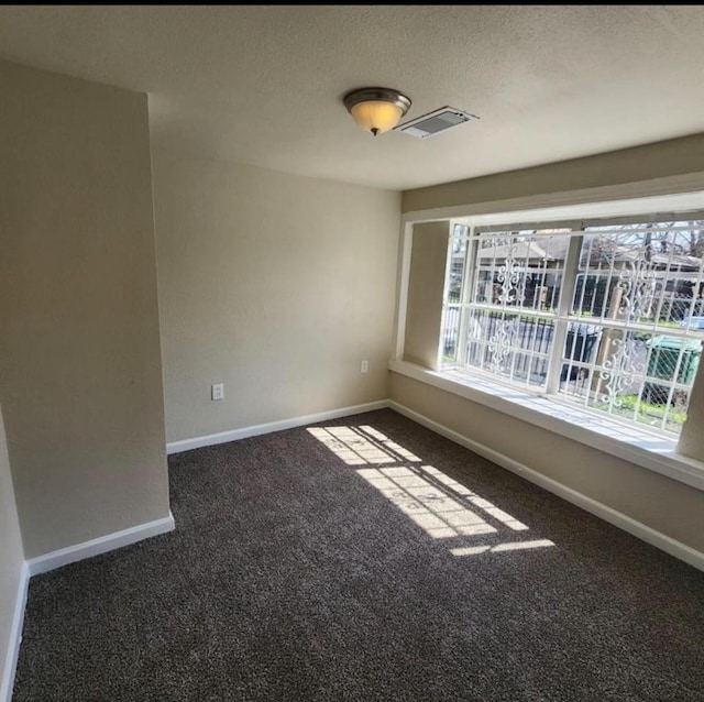 carpeted spare room featuring a textured ceiling, baseboards, and visible vents