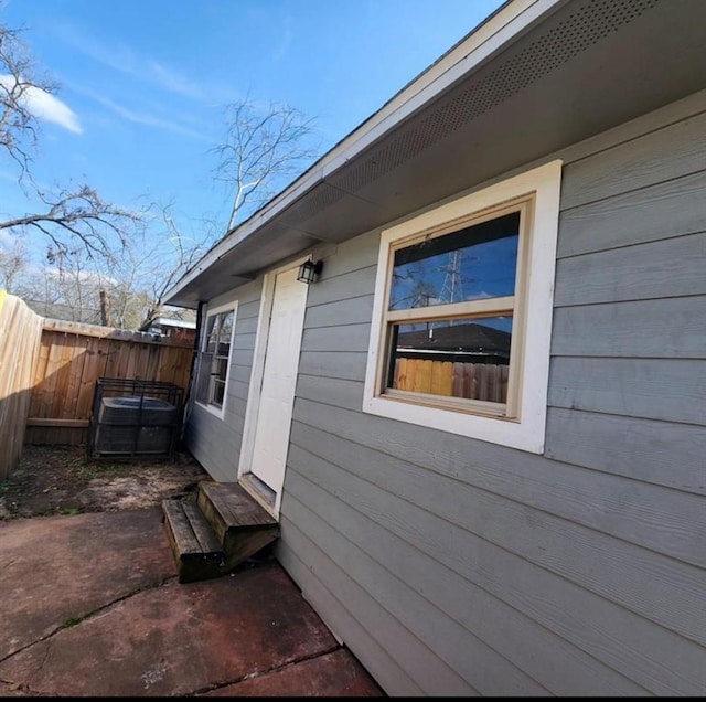 view of property exterior featuring entry steps, fence, and a patio