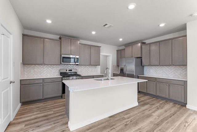 21624 Alberta Forest Cir, Magnolia, TX 77355 - kitchen with visible vents, a sink, appliances with stainless steel finishes, an island with sink, and decorative backsplash