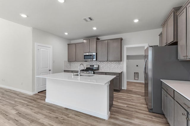 21624 Alberta Forest Cir, Magnolia, TX 77355 - kitchen featuring tasteful backsplash, visible vents, a sink, a kitchen island with sink, and stainless steel appliances